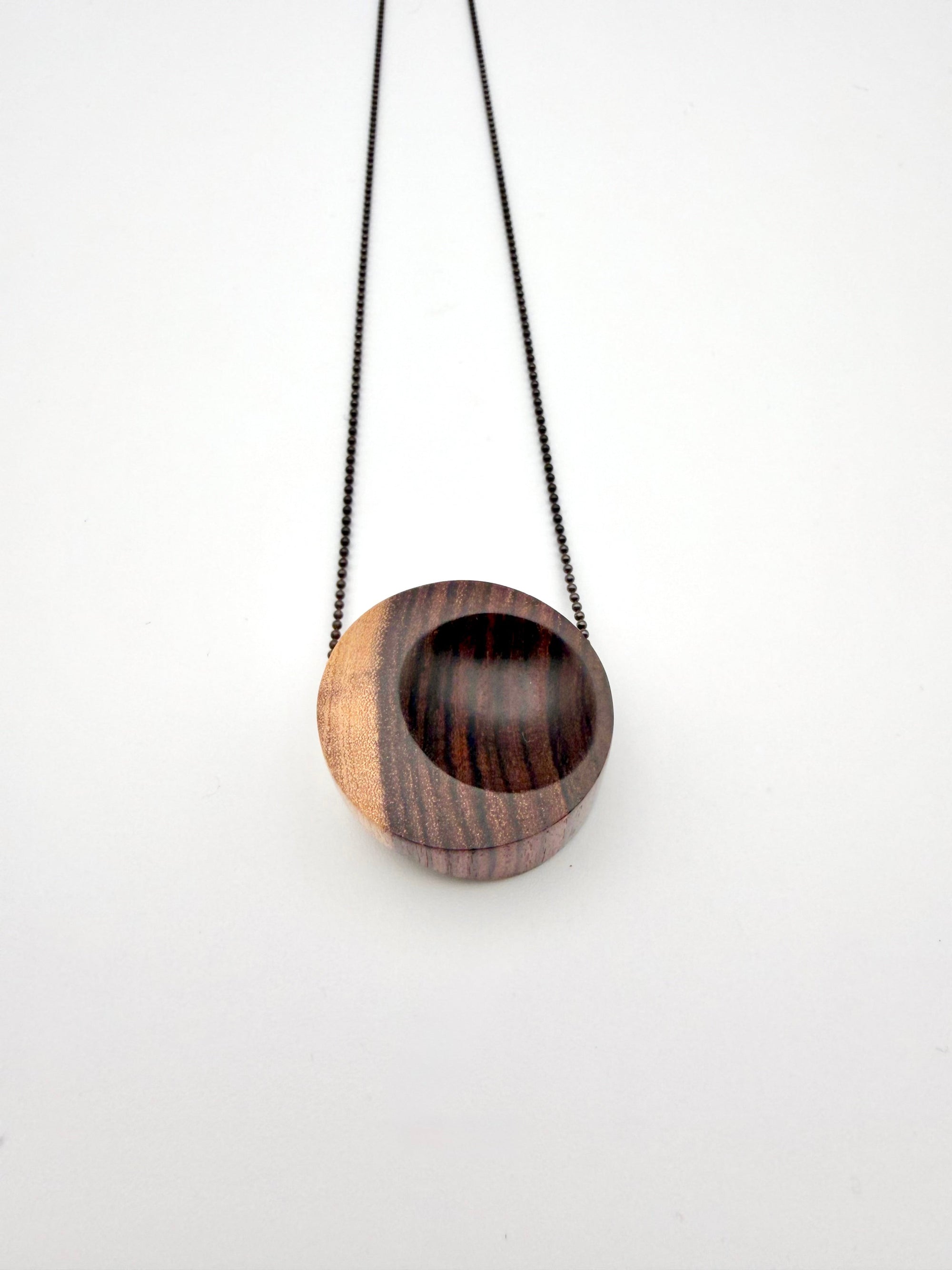 Wooden pendant necklace with two-tone design on a white background