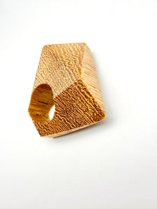Large wood sculpture ring with a textured surface on a white background