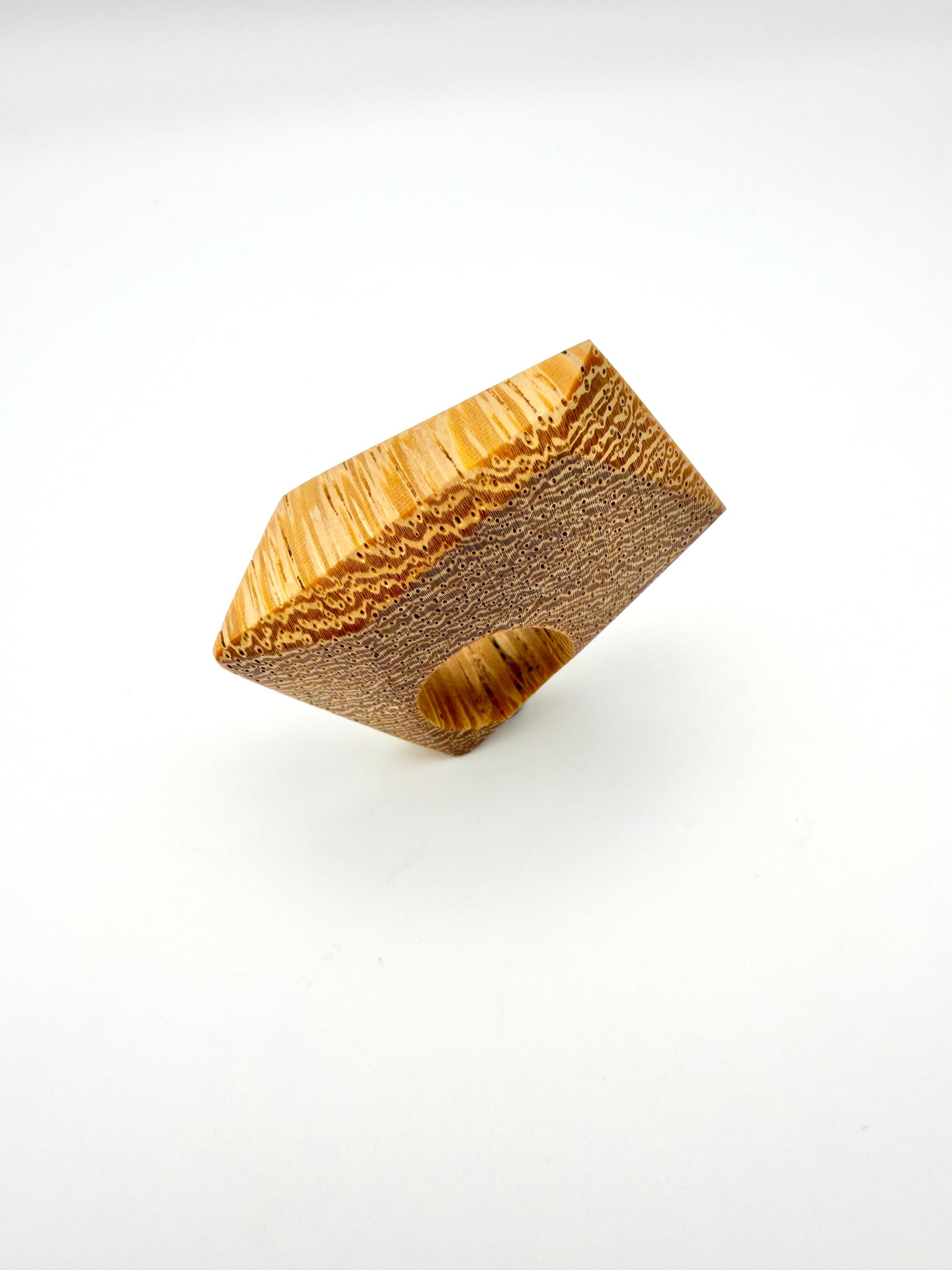 Blonde wood ring with textured surface on a white background