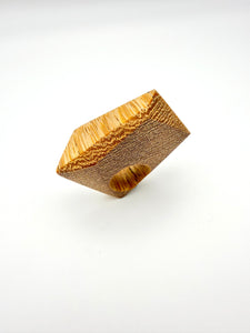Blonde wood ring with textured surface on a white background