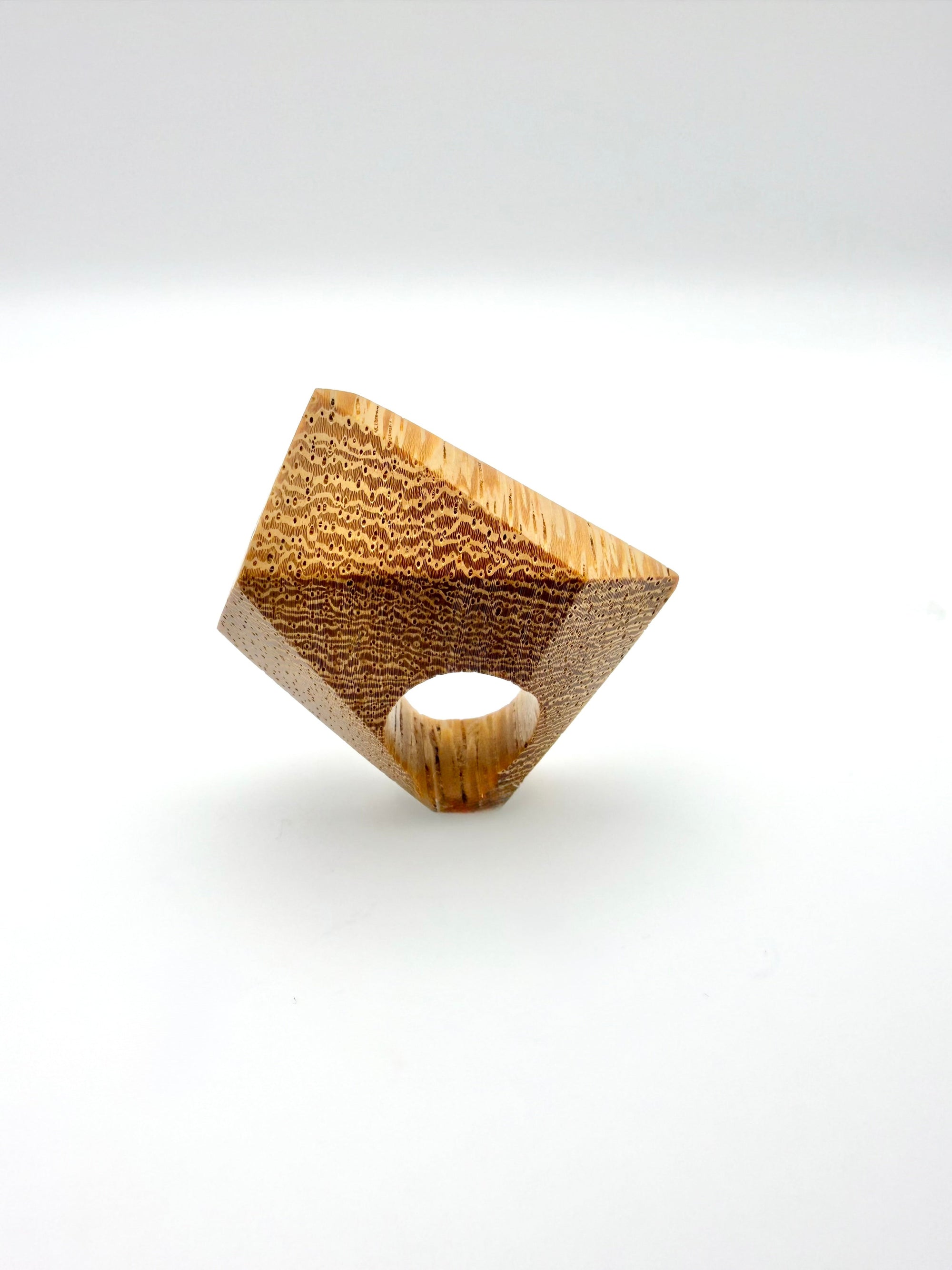 Wooden sculpture ring with a textured surface on a white background