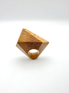 Wooden sculpture ring with a textured surface on a white background