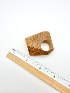 Wooden ring with a textured surface next to a ruler on a white background