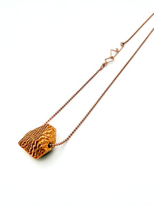 Blonde wood pendant with a dramatic grain pattern on rose gold ball chain and custom clasp on a white background
