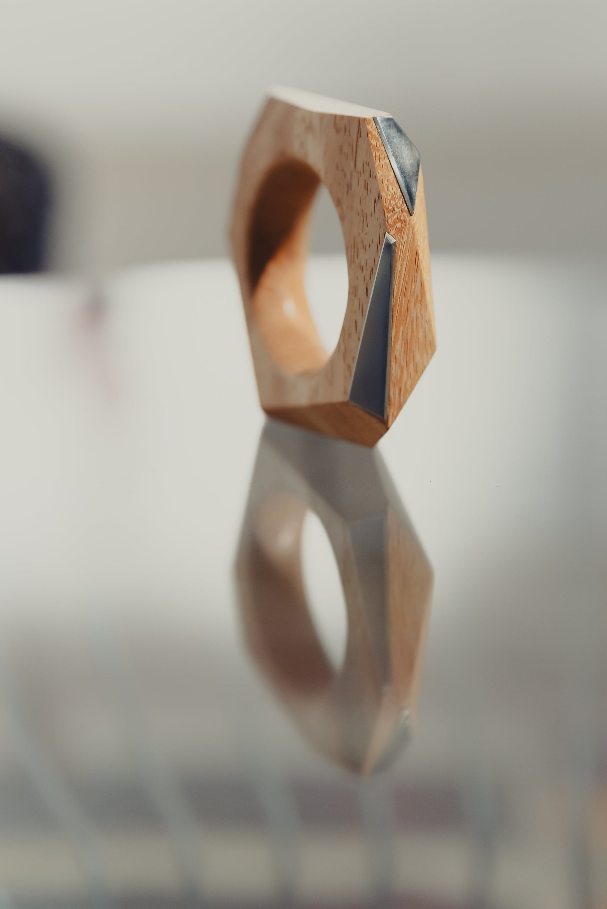 Wooden ring with geometric design on a reflective surface