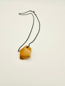 Geometric olivewood pendant on an oxidized silver chain with custom clasp on white background. 