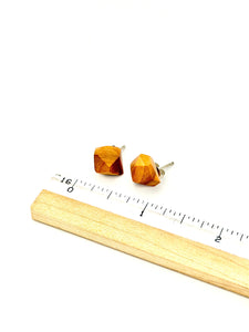 Wooden geometric earrings with a ruler for scale on a white background