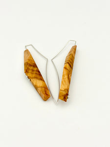 Olivewood asymmetric long narrow earrings with silver details and long web like ear wires on white background. 
