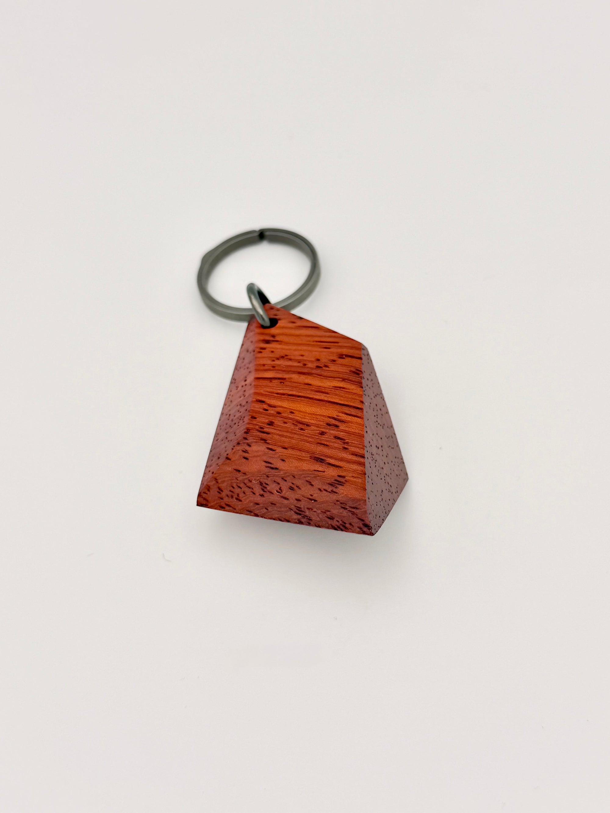 faceted geometric wood keychain with metal ring on a light gray background