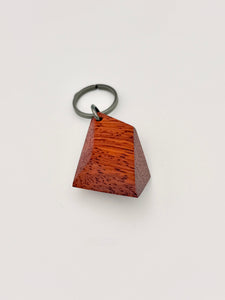 faceted geometric wood keychain with metal ring on a light gray background