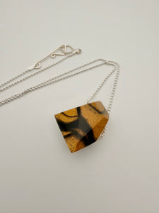 Necklace with a geometric polished wood pendant (resembling a stone) on a silver bead chain and light background