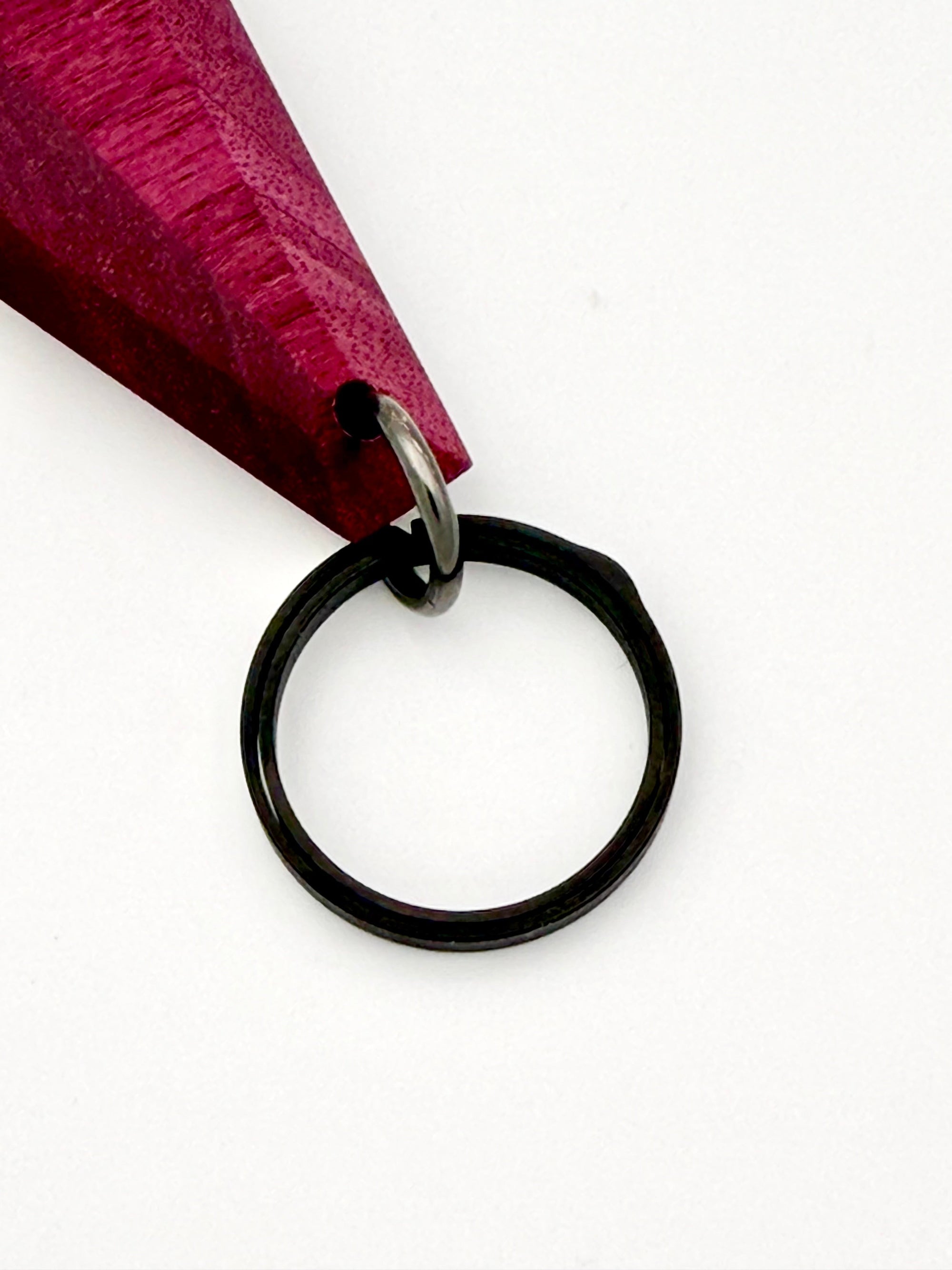 Black keychain ring attached to purple wood on a white background