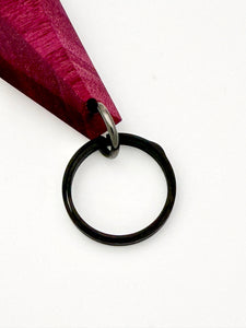 Black keychain ring attached to purple wood on a white background