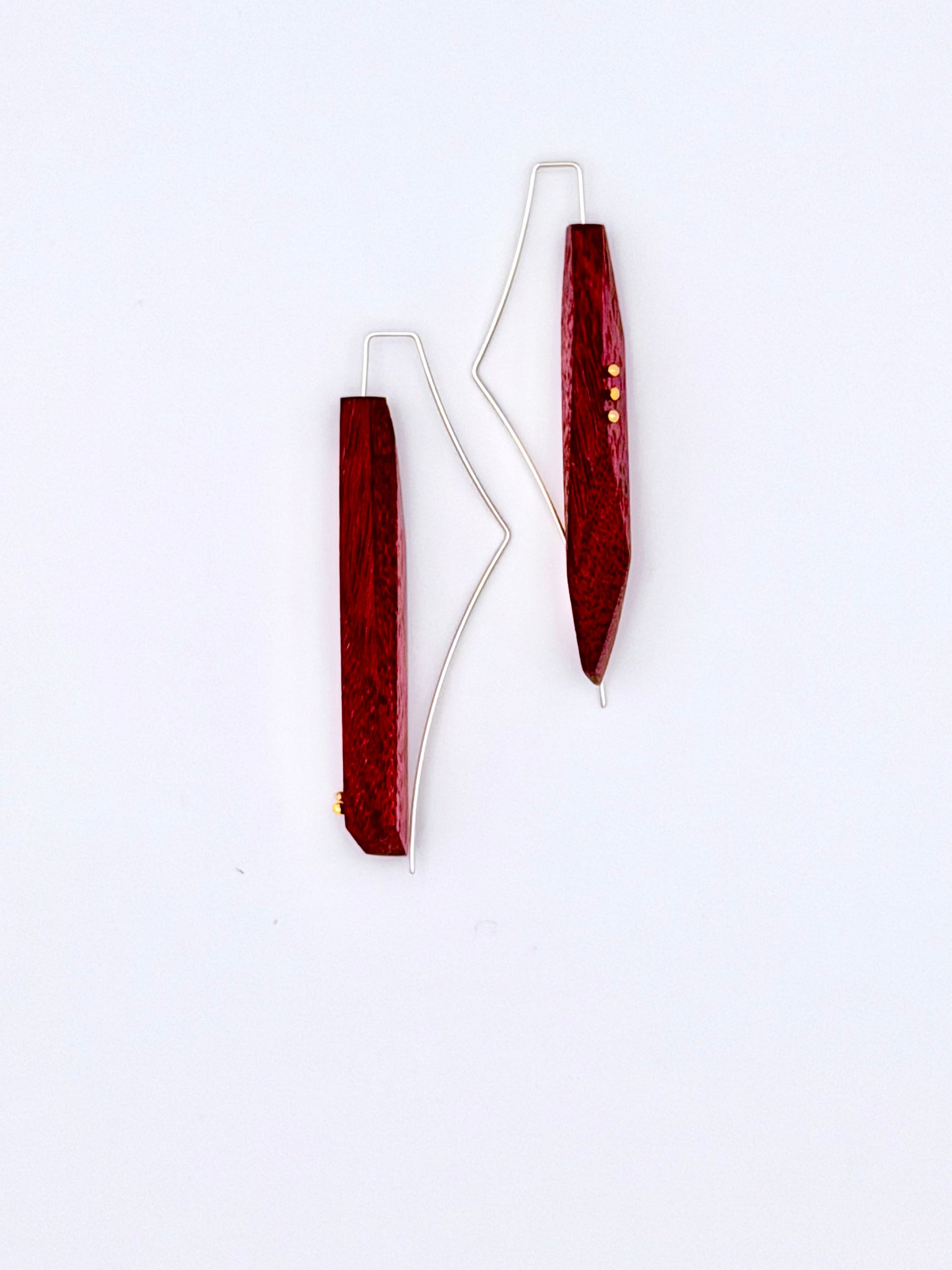 Pair of earrings with long purple geometric wood designs on a white background