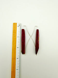 Two wood earrings with a ruler for scale on a white background