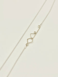 Silver bead chain with custom decorative clasp on white background. 