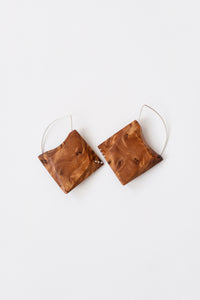 Ornate wood grain geometric earrings with Silver details and hoops on white background. 