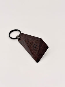 (Wenge) Dark brown and black wood keychain with geometric design on a light gray background