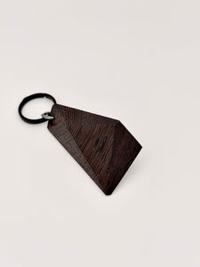 Wenge wood geometric keychain on a light gray background