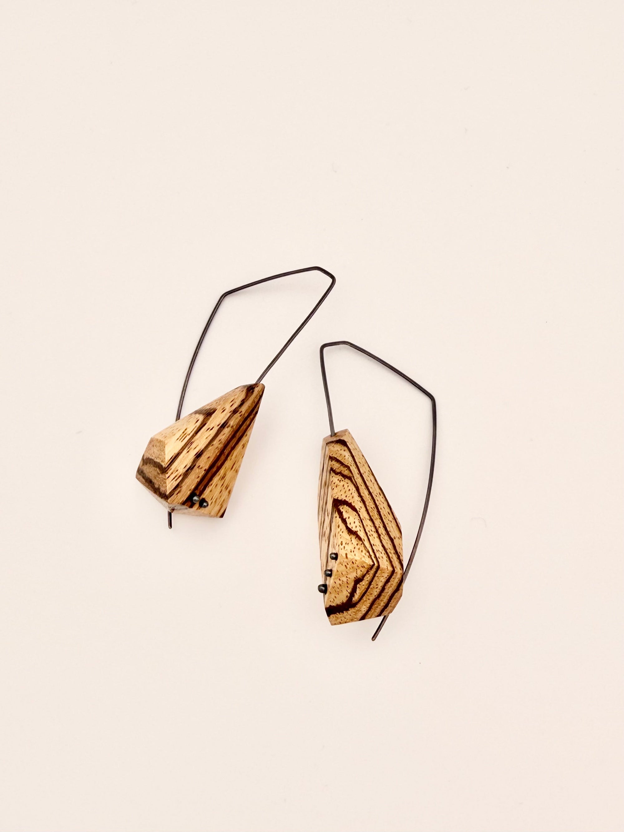 Asymmetrical zebrawood earrings  with 5 oxidized dot details and oxidized angular hoops on a white background. 