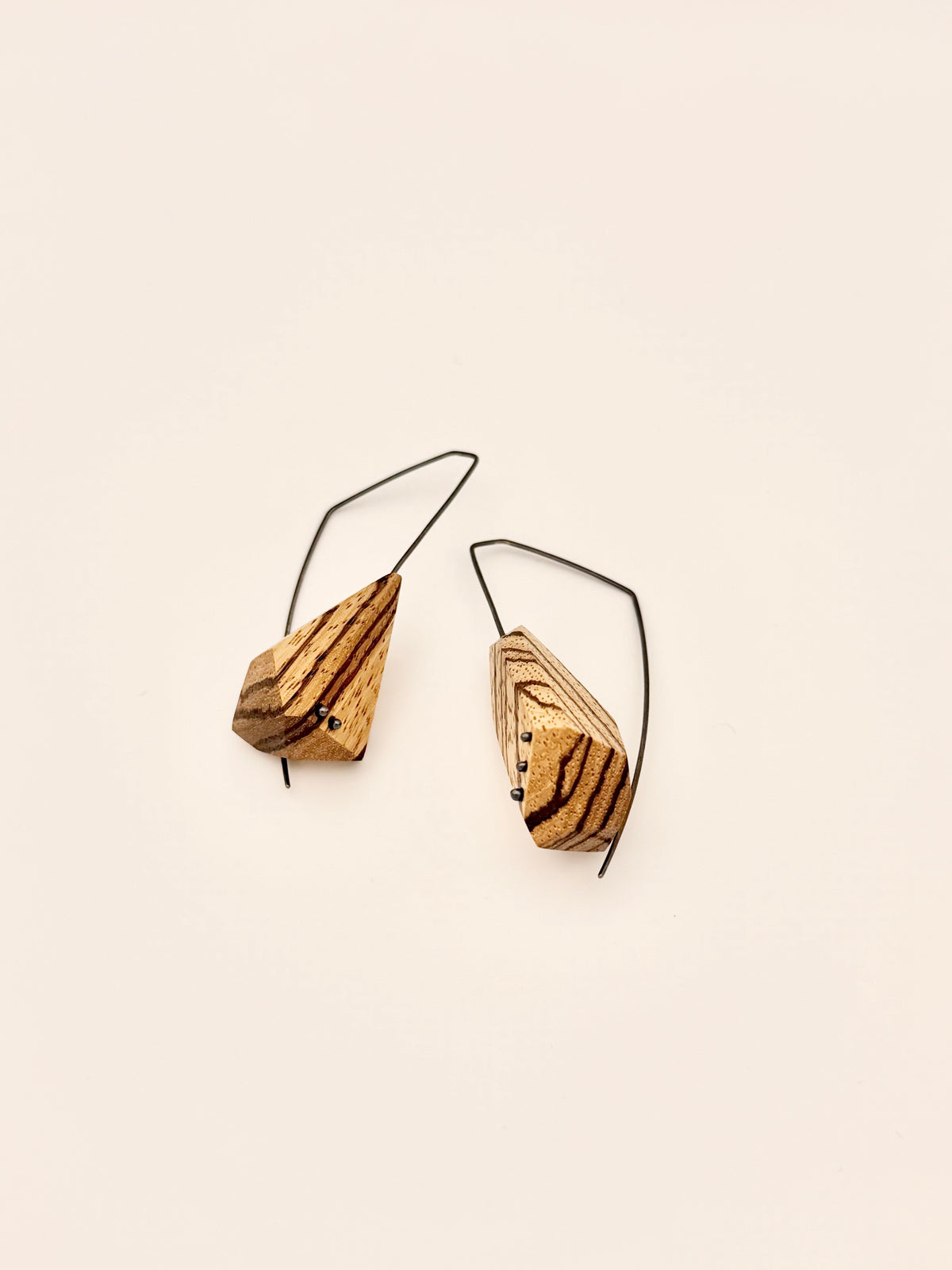 Asymetric Zebrawood geometric drop earrings with oxidized angular hoops and oxidized dot details in wood on white background. 