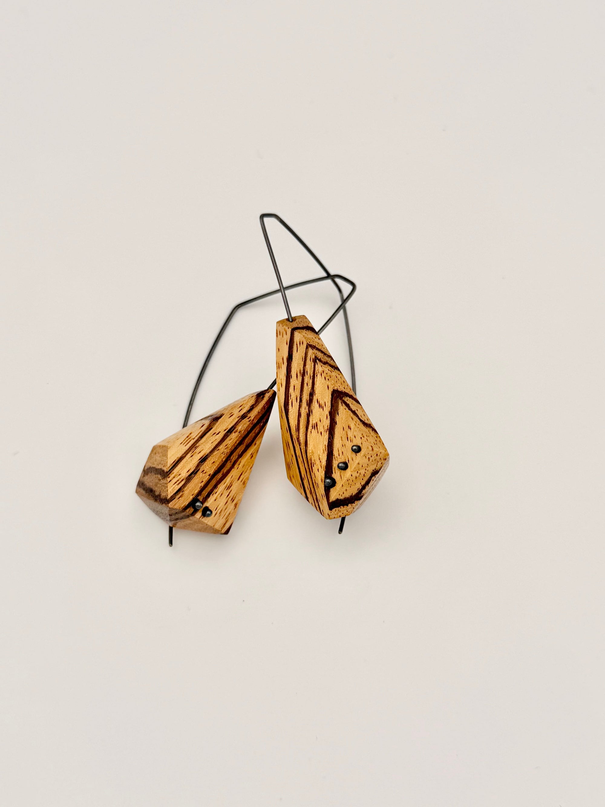 Wooden earrings with black wire on a light gray background
