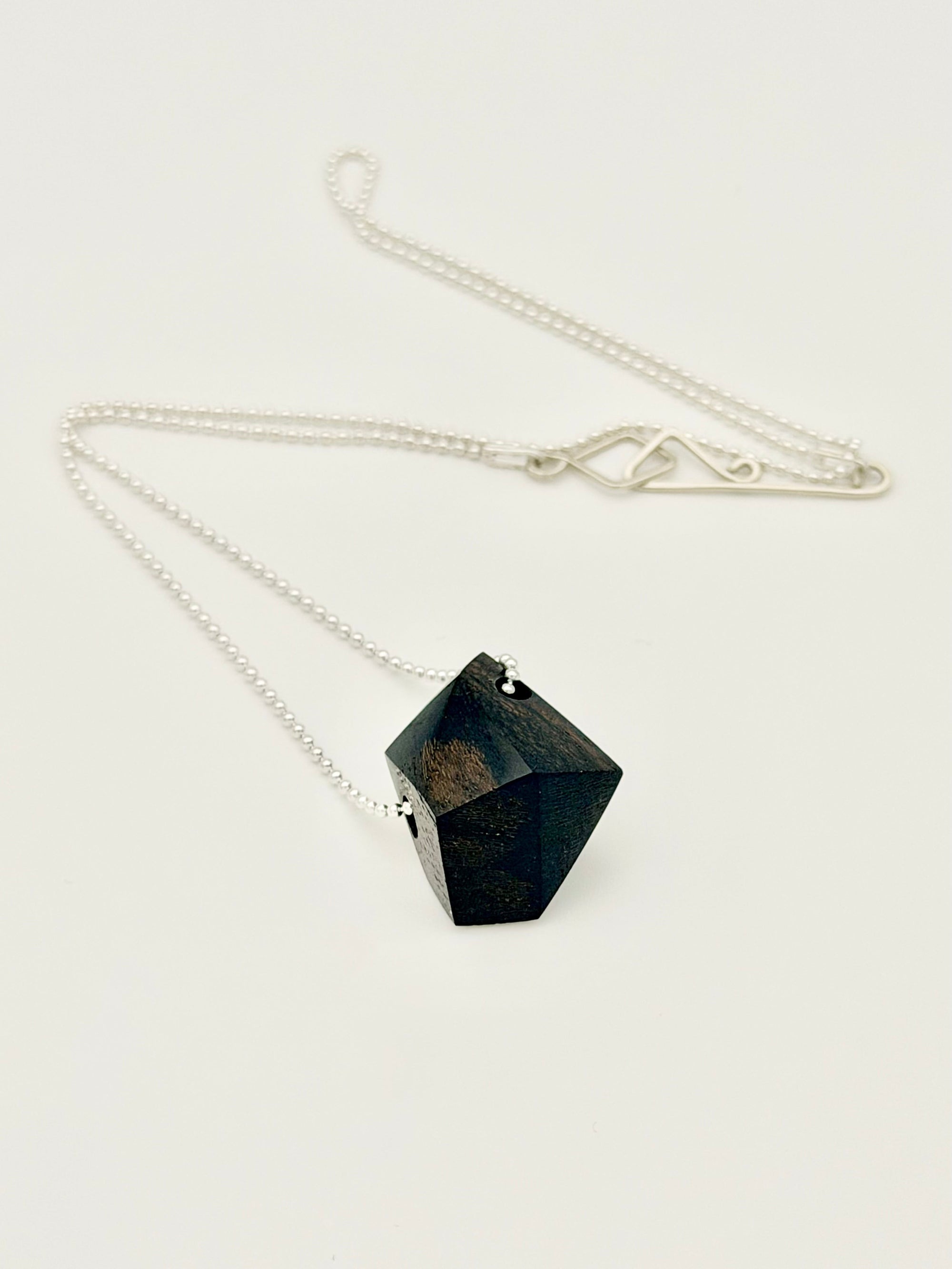 Necklace with a black geometric wood pendant on a silver ball chain displayed on a white background